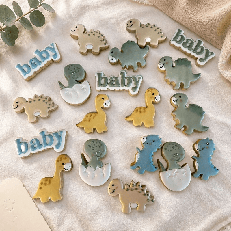 Pastel dinosaur baby shower cookies with onesie and footprint designs